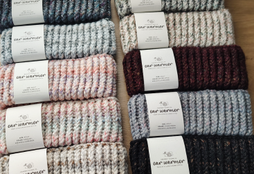 different colors of knitted ear warmers on a table